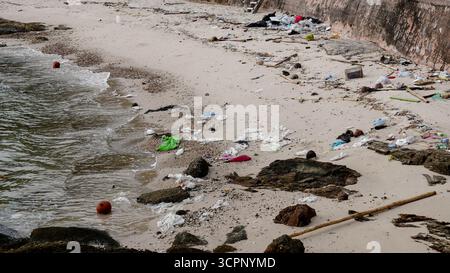 Umweltverschmutzung durch Plastikflaschen und Abfälle, die am Sandstrand in der Nähe des Meeres verstreut sind. Stockfoto