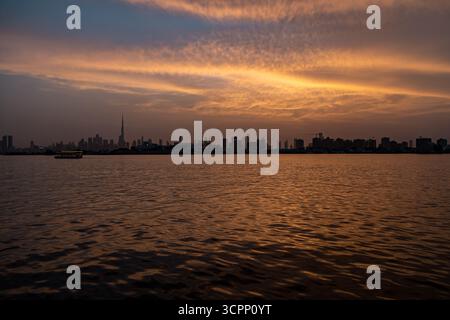 Stock Video über die szenische Skyline von Dubai bei Sonnenuntergang mit goldenem Himmel und Wasserkräuseln, Panoramablick vom Creek Harbour mit Booten und Yachten Stockfoto