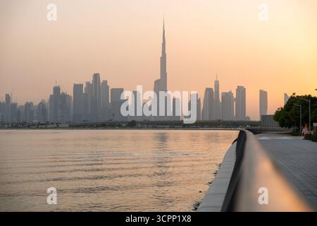 Skyline-Silhouette von Dubai Panoramablick bei Sonnenuntergang mit orangem Himmel und Creek-Ufer, hochauflösender Stadtlandschaft Hintergrund Stockfoto