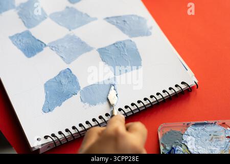 Acrylfarbe mischen mit Palettenmesser, Künstler erstellen strukturierte Muster auf Skizzenbuch für Kunstprojekt, Pastell Farben strukturierte Kunst auf weißer Dose Stockfoto