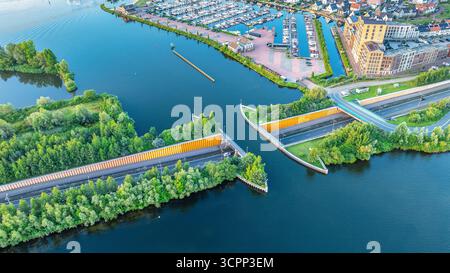 Blick auf die Stadt mit der Straße über den Kanal, die einzigartige Unterwasserbrücke schafft. Interessante Häuser und Segelhafen auf dem Wasser. Veluwemeer-Garderwijk Aque Stockfoto