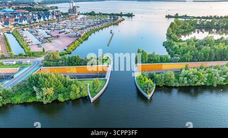 Blick auf die Stadt mit der Straße über den Kanal, die einzigartige Unterwasserbrücke schafft. Interessante Häuser und Segelhafen auf dem Wasser. Veluwemeer-Garderwijk Aque Stockfoto