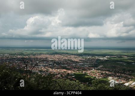 Großer Panoramablick auf Vrsac und die umliegende serbische Landschaft unter einem dramatischen bewölkten Himmel im Frühling. Stockfoto