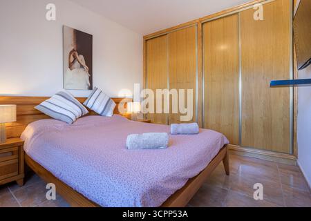 Schlafzimmer mit Holzbett, großem Kleiderschrank und moderner Einrichtung. Stockfoto