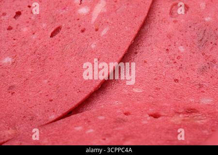 Makrofoto frischer Scheiben rosafarbenes verarbeitetes Fleisch. Nahaufnahme von dünn geschnittenem Salamifleisch. Hintergründe im Zusammenhang mit Feinkostprodukten und Lebensmittelverarbeitung. Stockfoto