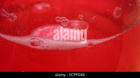 Brausetablette löst sich in Wasser auf. Makrofoto der Brausetablette, die das Wasser rot färbte. Eine lösliche Pille. Stockfoto