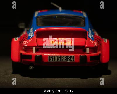 Oldtimer-Rallye-Modell dunkler Hintergrund - Nahaufnahme einer detaillierten, bunten Miniatur-Nachbildung eines klassischen Porsche-Rallye-Autos mit Sponsoring-Abziehbildern, d Stockfoto