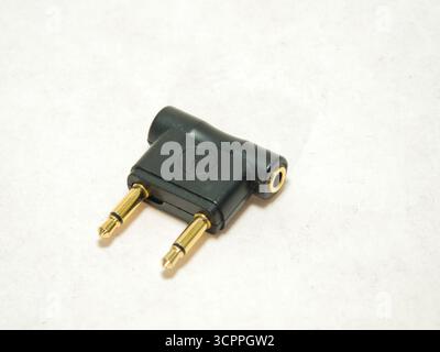 Flugzeugkopfhöreranschluss-Audioadapter - Nahaufnahme eines schwarzen, zweipoligen Flugzeugkopfhöreranschlussadapters auf weißem Hintergrund. Unverzichtbares Zubehör für Stockfoto