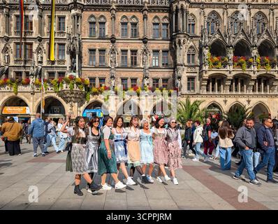 München, Deutschland. September 2025. Besucher in traditionellen Dirndl-Kleidern posieren für Fotos am Marienplatz in München, Bayern, Deutschland, am 27. September 2025. Die Gruppe feiert das Oktoberfest in der Innenstadt, bevor es zum Festgelände geht. (Foto: Michael Nguyen/NurPhoto) Credit: NurPhoto SRL/Alamy Live News Stockfoto