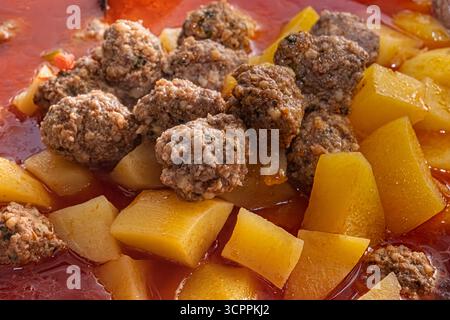Türkischer Fleischeintopf mit Kartoffeln in roter Brühe. Aus nächster Nähe sehen Sie Sulu Köfte, ein traditionelles Essen mit kleinen Fleischbällchen und Kartoffelwürfeln. Stockfoto