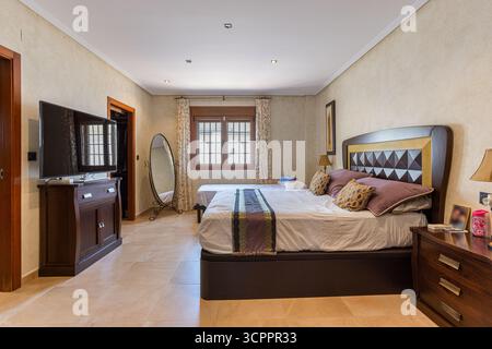 Schlafzimmer mit großem Bett, Holzmöbeln und klassischer Einrichtung. Stockfoto