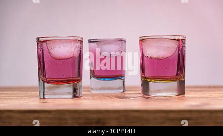 Drei bunte Schussgläser mit Eis. Ein lebhaftes Trio von Shot-Gläsern gefüllt mit bunten Getränken. Selektiver Fokus. Stockfoto
