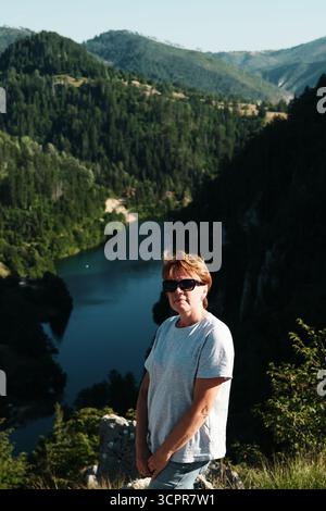 Porträt einer Frau in lässigem Outfit und Sonnenbrille vor dem Spajici-See im Tara-Nationalpark, Serbien. Stockfoto