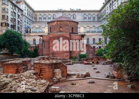 Die alte Rotunde des Heiligen Georg in Sofia, Bulgarien, eine frühchristliche Kirche aus rotem Backstein, umgeben von römischen Ruinen und modernen Gebäuden. Stockfoto
