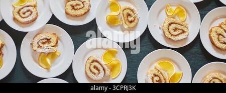 Schwammrollen mit Marmelade und einer Scheibe Orange auf weißen Tellern. Hintergrund. Banner Stockfoto