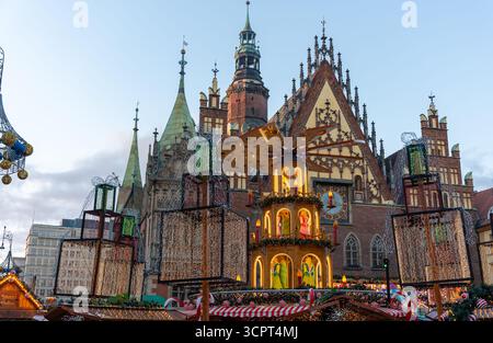 Bezauberndes Karussell mit weihnachtlicher Pyramide mit beleuchteter Holzstruktur und festlicher Dekoration vor der prächtigen gotischen Kathedrale in europäischer Marke Stockfoto