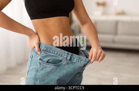 Unverkennbare Schwarze Dame Mit Bauchmuskeln, Die Übergroße Jeans In Der Halle Tragen Stockfoto