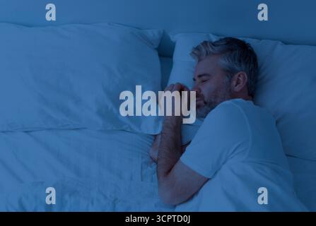 Top Aussicht auf einen Mann, der nachts alleine im Bett schläft Stockfoto
