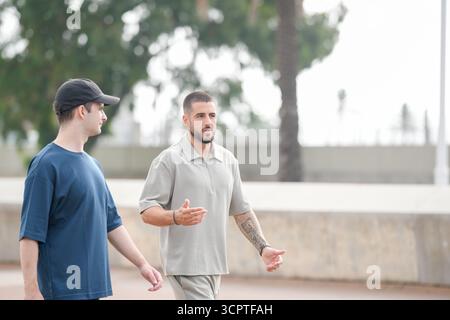 Zwei Männer laufen zusammen in einem Park. Einer von ihnen trägt einen schwarzen Hut. Die Szene ist lässig und entspannt Stockfoto