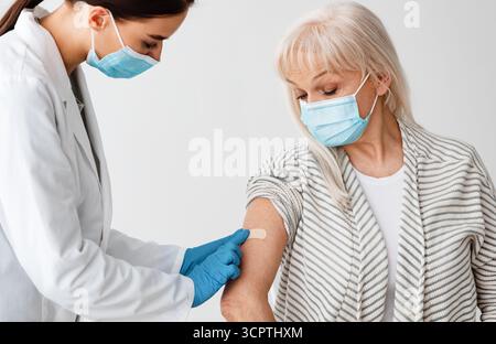 Reifer Patient, Der Gegen Covid-19 Geimpft Wird, Arzt, Der Gips Anwendet Stockfoto