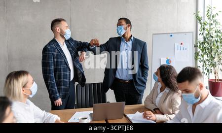 Zwei Geschäftsleute In Masken Stoßen Ellbogen Während Corporate Meeting Indoor Stockfoto