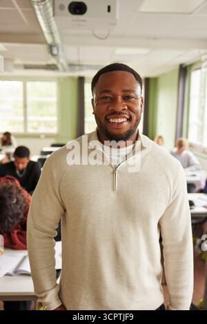 Porträt eines selbstbewusst lächelnden männlichen Lehrers, der im Klassenzimmer der Junior High School steht Stockfoto