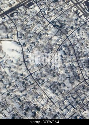 Eine Luftaufnahme zeigt ein schneebedecktes Vorstadtviertel mit Häusern, Bäumen und Straßen. Stockfoto