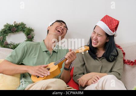 Weihnachten glückliches Paar zeigt Liebe, Weihnachten Winterfreude zu Hause spielt Ukulele, die herzlich mit lacht Stockfoto