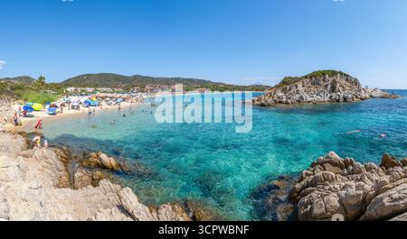 Sithonia, Griechenland - 02. September 2025:Kalamitsi Beach in Sithonia, Griechenland, mit türkisfarbenem Wasser, goldenem Sand, Sonnenschirmen, felsige Inselchen und eine tr Stockfoto