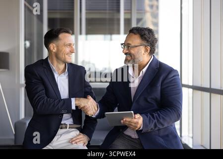 In der modernen Bürolounge tauschen sich zwei selbstbewusste Profis aus Stockfoto