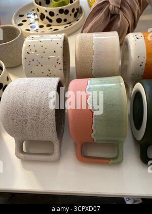 Farbenfrohe Keramikbecher in verschiedenen Designs auf einem Regal, ideal für Heimdekorateure. Mobiles Foto Stockfoto