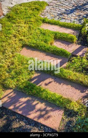 Weg mit großen Steinplatten durch einen wunderschön bepflanzten Garten Stockfoto
