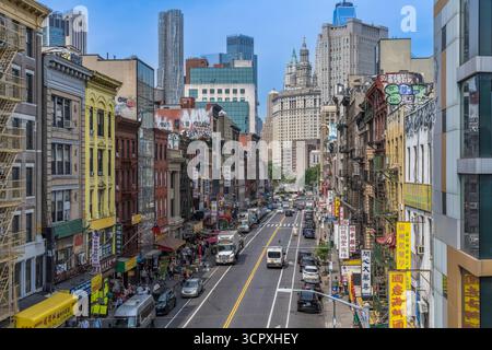 Chinatown Straßenszene mit Verkehr, Geschäften und Wolkenkratzern im Hintergrund, Manhattan, New York City, USA. Juni 2025. Stockfoto