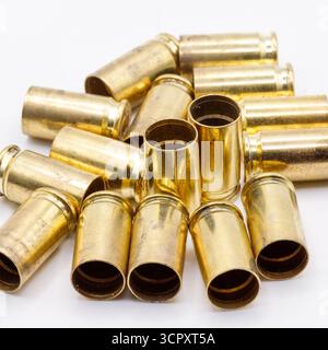 Ein Stapel gebrauchter Messingkugeln ist auf einer weißen Oberfläche verstreut und zeigt einen warmen, goldenen metallischen Glanz und etwas Schmutz. Stockfoto