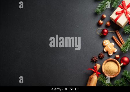 Weihnachten flach gelegt Hintergrund. Lebkuchenkekse, Geschenkbox, Gewürze und Weihnachtsdekoration auf Schwarz. Stockfoto