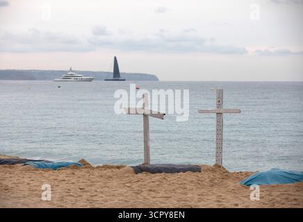 Palma, Spanien. September 2025. Rettungsschwimmer haben Kreuze am Strand Can Pere Antoni aufgestellt, um auf ihre prekären Arbeitsbedingungen aufmerksam zu machen. Die Rettungsschwimmer auf den Balearen wollen ab dem 28. September jedes Wochenende auf unbestimmte Zeit streiken, um ihre Forderungen nach besseren Arbeitsbedingungen zu erfüllen. Quelle: Clara Margais/dpa/Alamy Live News Stockfoto