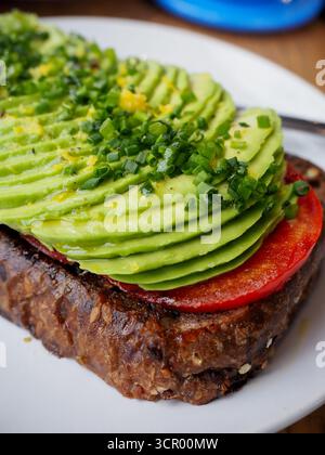 Nahaufnahme von frischem Avocado Toast mit Tomaten und Schnittlauch auf Vollkornbrot Stockfoto