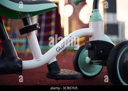 Tyumen, Russland-8. Juli 2025: Balancerad globber parkt bei Tageslicht auf Spielplatzfläche in der Nähe von farbenfrohen Spielstrukturen Stockfoto
