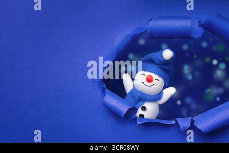Schneemann in blau gerissenem Papierloch mit Kopierraum Stockfoto