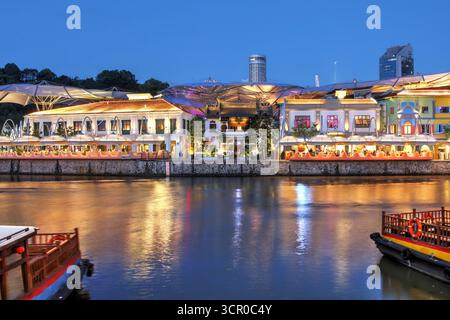 Abend auf dem Singapore River mit Clarke Quay, einem historischen Viertel, das zu einem Einkaufszentrum umgebaut wurde, mit einem Angel Canopy, um eine niedrigere Temperatur beizubehalten Stockfoto