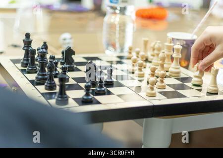 In einer entspannten Umgebung treten zwei Spieler in einem Schachspiel an, wobei sie sich stark auf ihre Strategie und ihre Züge konzentrieren. Auf dem sind verschiedene Schachfiguren aufgestellt Stockfoto