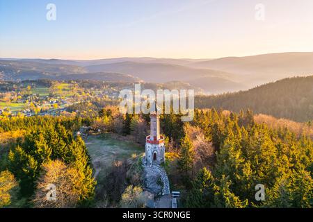 Der Stepanka Aussichtsturm steht anmutig inmitten üppiger Frühlingsgrünen in Korenov, Tschechien. Das Morgenlicht strahlt ein warmes Licht über die malerische Landschaft und die umliegenden Hügel. Stockfoto