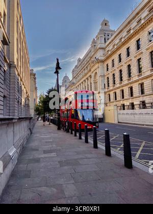 Roter Doppeldeckerbus, der durch die historische Londoner Straße mit klassischer Architektur fährt Stockfoto