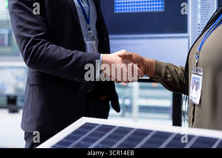 Investoren, die nach der Untersuchung der Oberfläche des Solarmoduls Handshake machen, sind mit der Effizienz des Designs zufrieden. Geschäftsleute schütteln die Hände, treffen sich, um über technische Verbesserungen an Solarzellen zu sprechen, Nahaufnahme Stockfoto