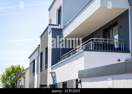 Ein modernes Apartmentgebäude mit eleganten Linien und großen Balkonen. Der klare blaue Himmel bietet eine helle Kulisse für das gut gestaltete Archi Stockfoto