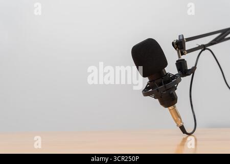 Nahaufnahme eines professionellen Mikrofons mit Pop-Filter am verstellbaren Arm über dem Holztisch, der Podcast, Aufnahme, Übertragung, Voice-Over darstellt st Stockfoto