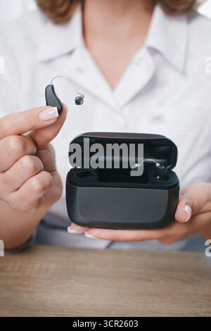 Hörgerät zum Aufladen von Patienten in einem speziellen tragbaren Smart Charger mit integrierter Powerbank. Die Tasche in den Händen hält Hörgeräte trocken und sicher Stockfoto
