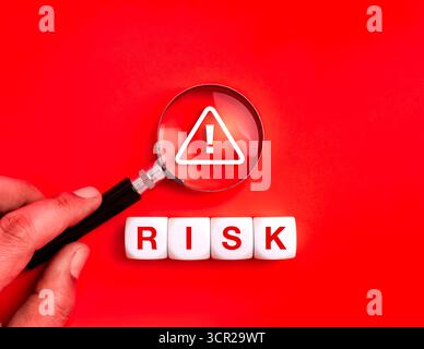 Lupe mit Fokus auf Warnzeichen und WORTRISIKO auf rotem Hintergrund. Konzept für Cybersicherheit, Datenschutz, Online-Betrugswarnung, Betrugserkennung Stockfoto