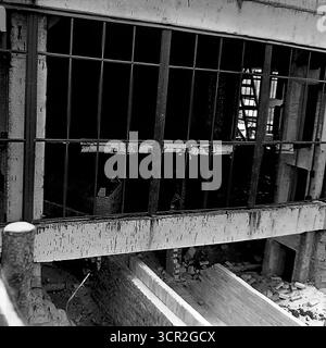 Nahaufnahme eines großen, unglasierten Fensters an der Fassade eines neuen Industriebaus in Sloviansk, ukrainische SSR, um 1985. Dieses detaillierte Schwarzweiß-Foto hebt die Rohtexturen der brutalistischen Architektur hervor, von den rauen Betonflächen bis zu den unfertigen Ziegelsteinen darunter. Es erfasst eine Zwischenphase des Bauprozesses und symbolisiert die grundlegende, konstruktive Arbeit, die die friedliche Donbass-Region prägte Stockfoto
