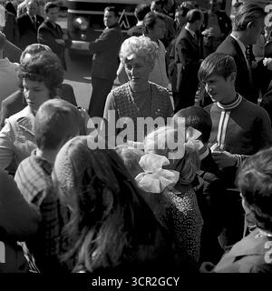 Eine Menschenmenge von Einheimischen, darunter Frauen, Männer und Kinder mit großen festlichen Haarschleifen, versammelt sich, um an der Feierlichkeiten zum Stadttag auf den Straßen von Sloviansk, ukrainische SSR, um 1985 teilzunehmen. Dieses ehrliche Schwarzweiß-Foto fängt die lebendige und gemeinschaftliche Atmosphäre eines sowjetischen Feiertags ein, bietet einen Einblick in das tägliche Leben und die soziale Struktur der Stadt und symbolisiert das lebendige, gemeinsame Gemeinschaftserlebnis der friedlichen Donbass-Region. Stockfoto
